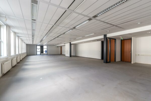Leegstaand, modern kantoorpand met grote ramen en systeemplafond aan De Wel.